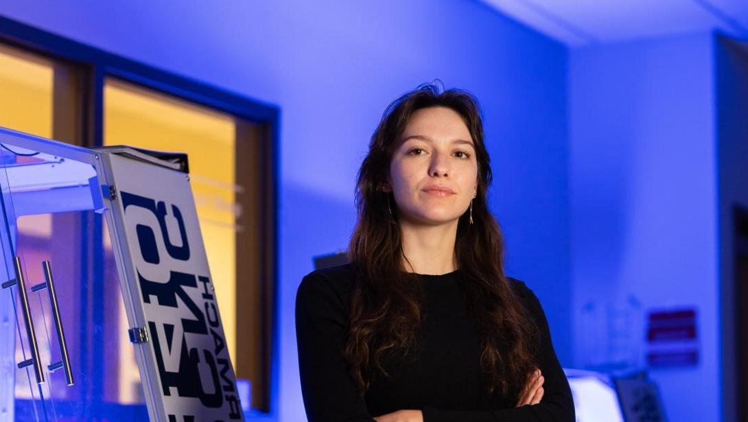 A student stands with arms crossed in a lab