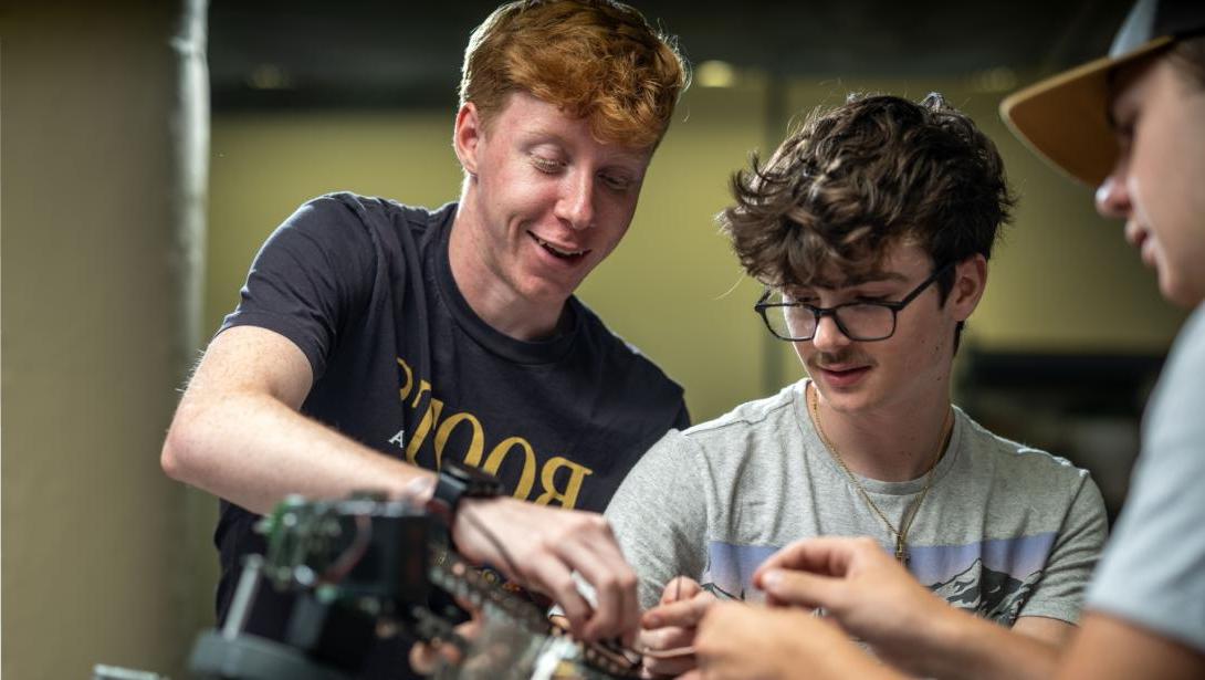 Three students using equipment