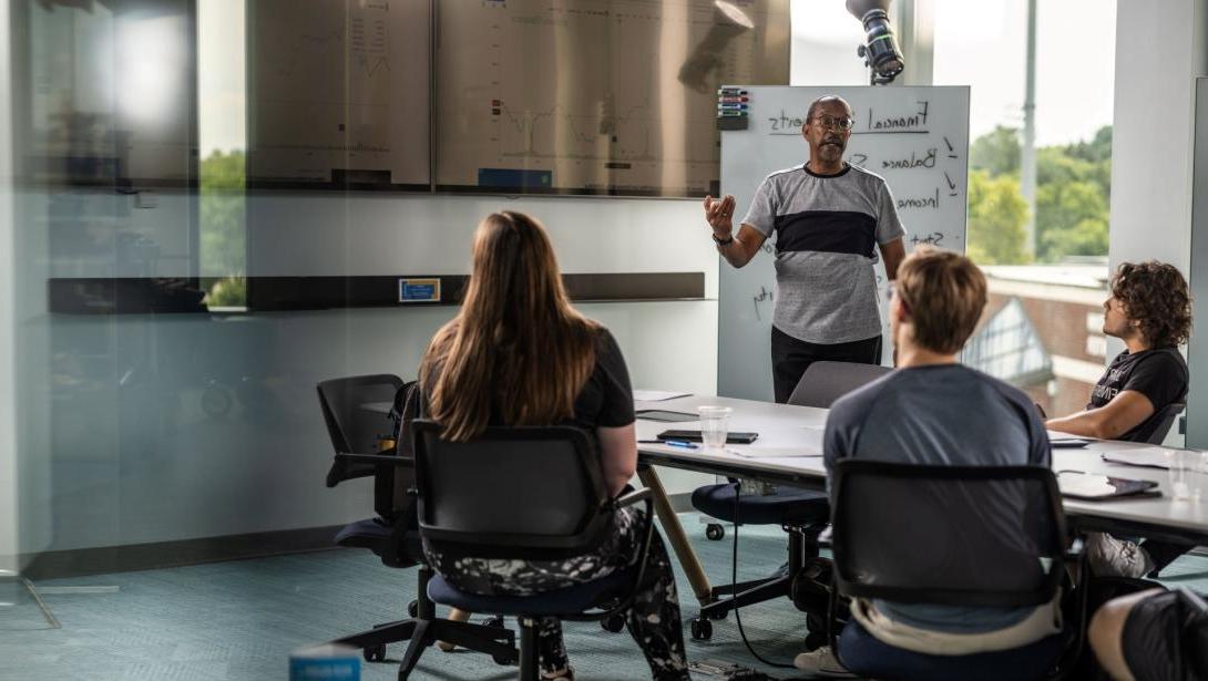 A professor teaches a group of students sitting at a table in the Learning Commons